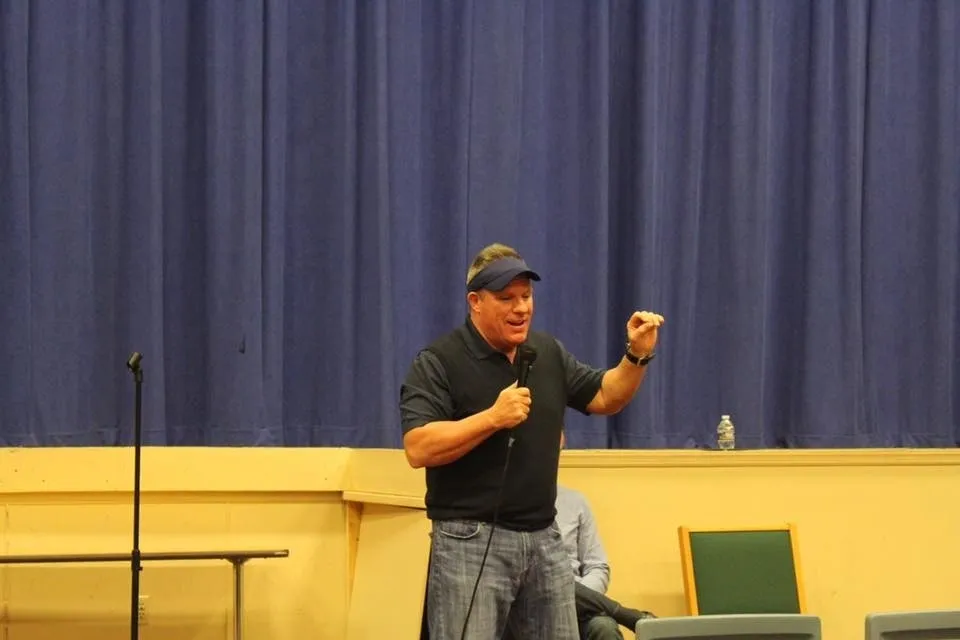 Man speaking into microphone before blue curtain