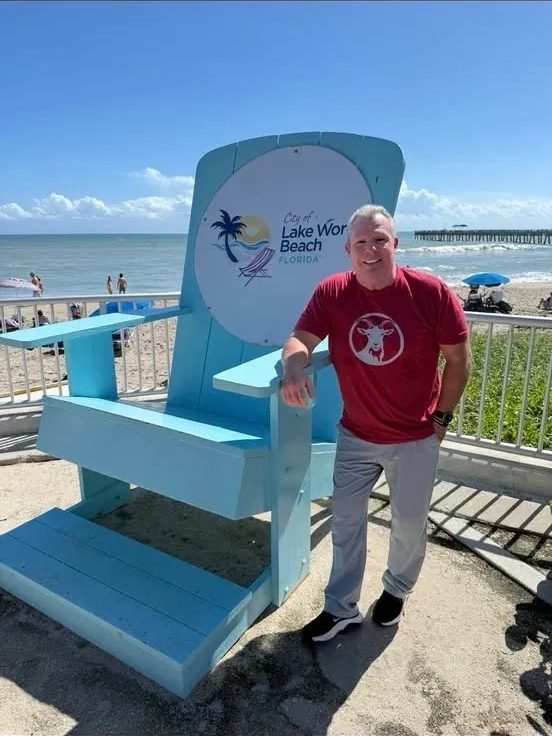 Man posing beside oversized blue beach chair