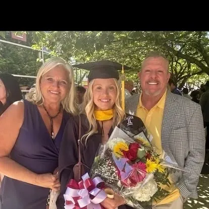 Graduate in cap and gown with proud parents