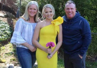 Woman in yellow dress holding flowers with couple
