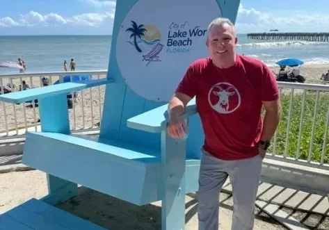 Man standing by large blue beach chair.