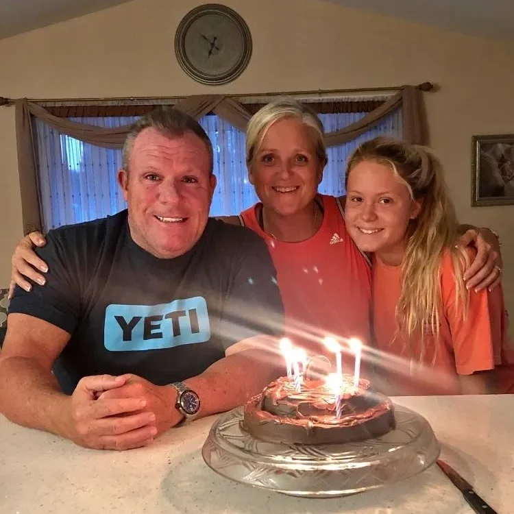 Family celebrating birthday with lit cake.