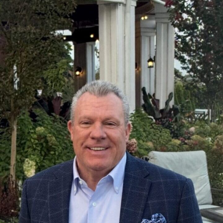 Smiling man outdoors in a suit jacket.