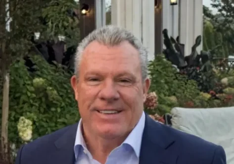 Smiling man in suit outside a building.